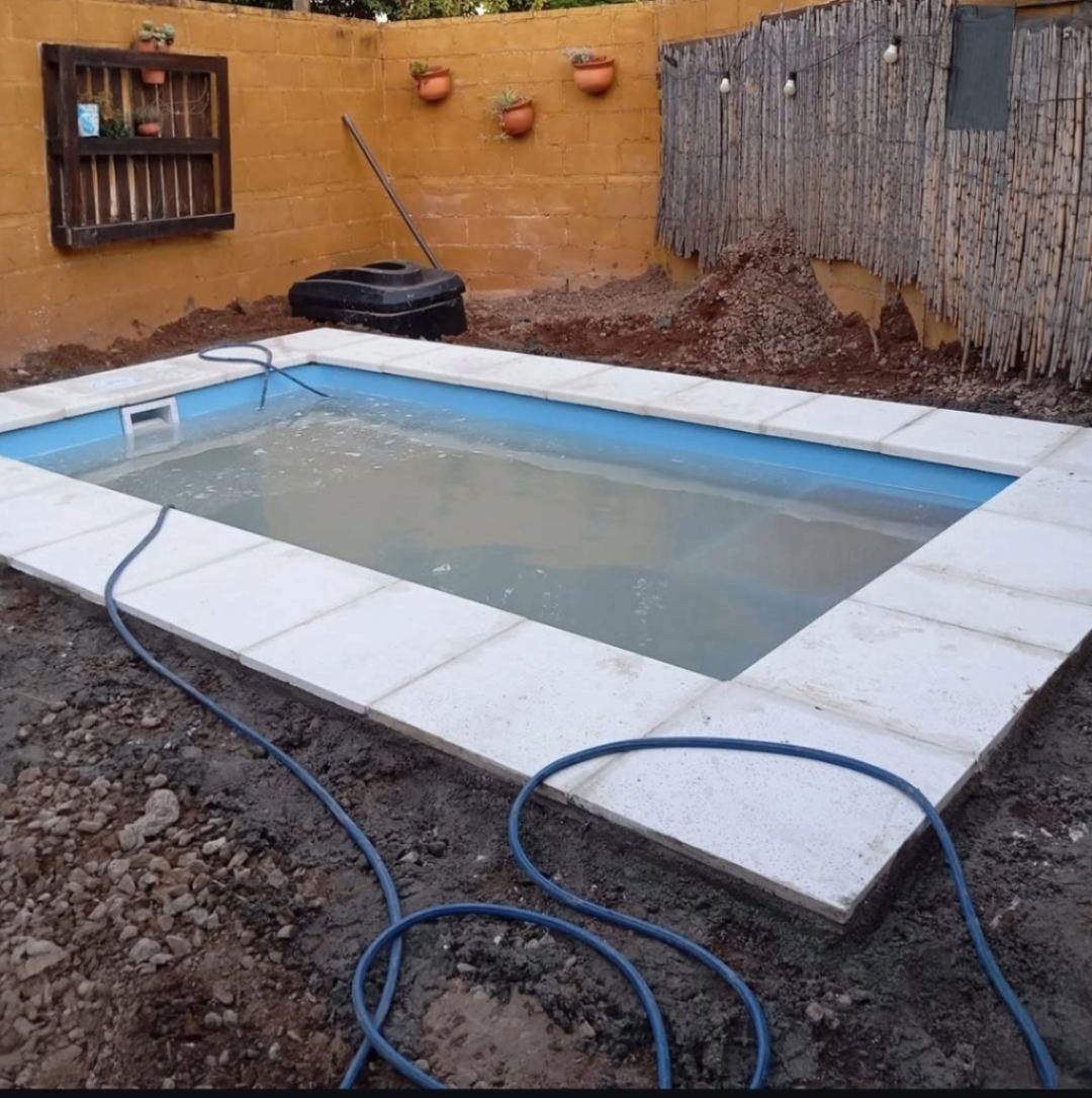 Pileta recién instalada con solado de cerámicos blancos, aún llenándose