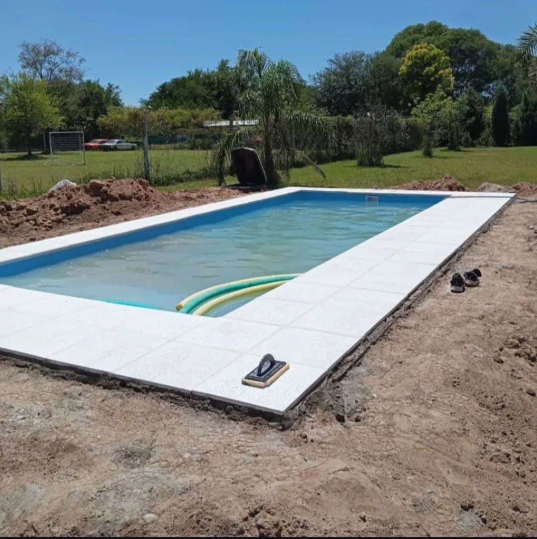 Pileta rectangular terminada en un jardín amplio con parque